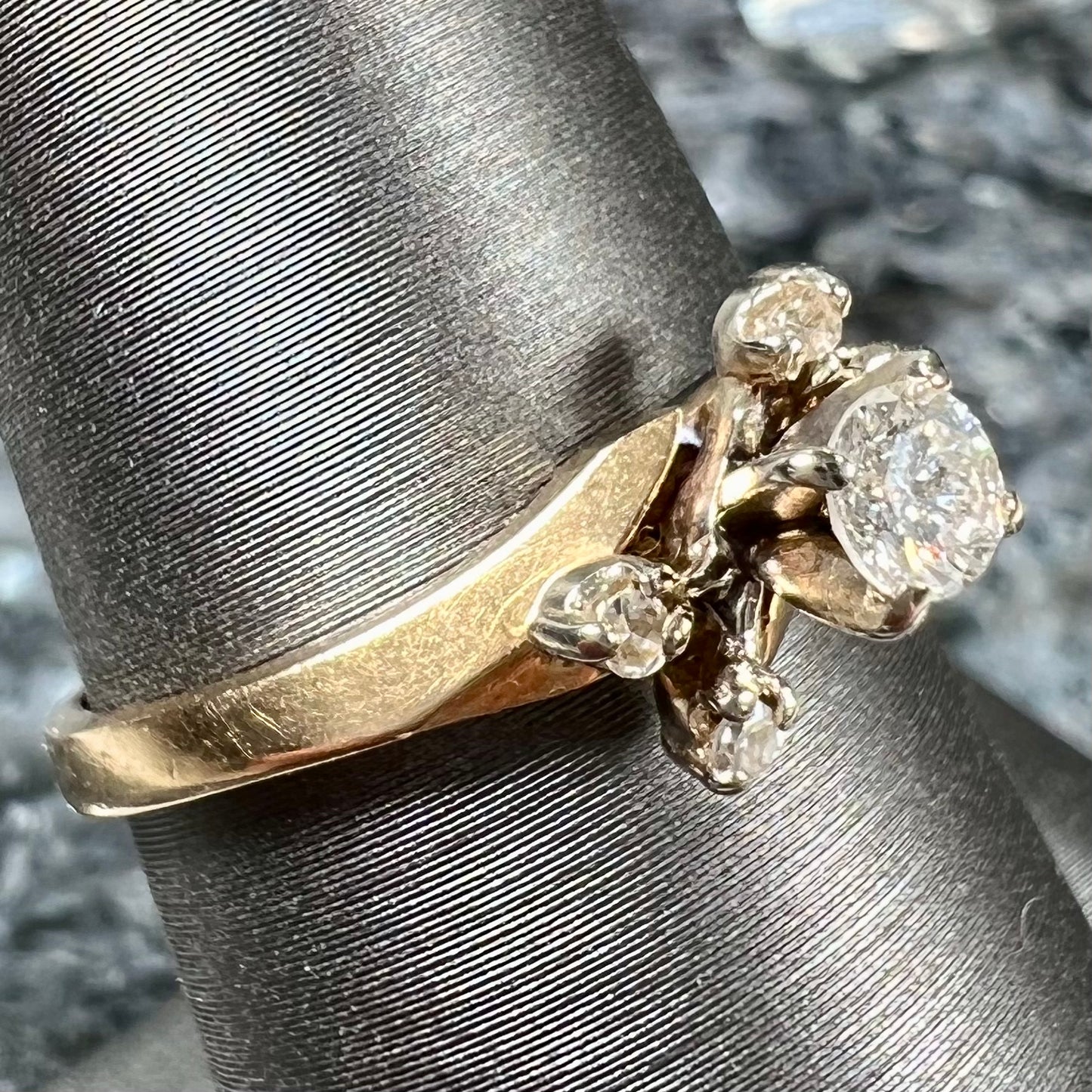 A yellow gold high-set diamond ring with four side diamonds.