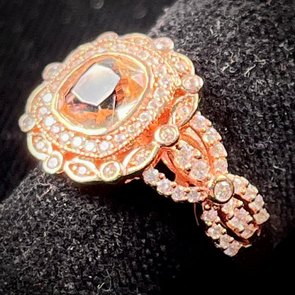 A rose gold plated ring set with a cushion cut morganite stone surrounded by cubic zirconia halos.
