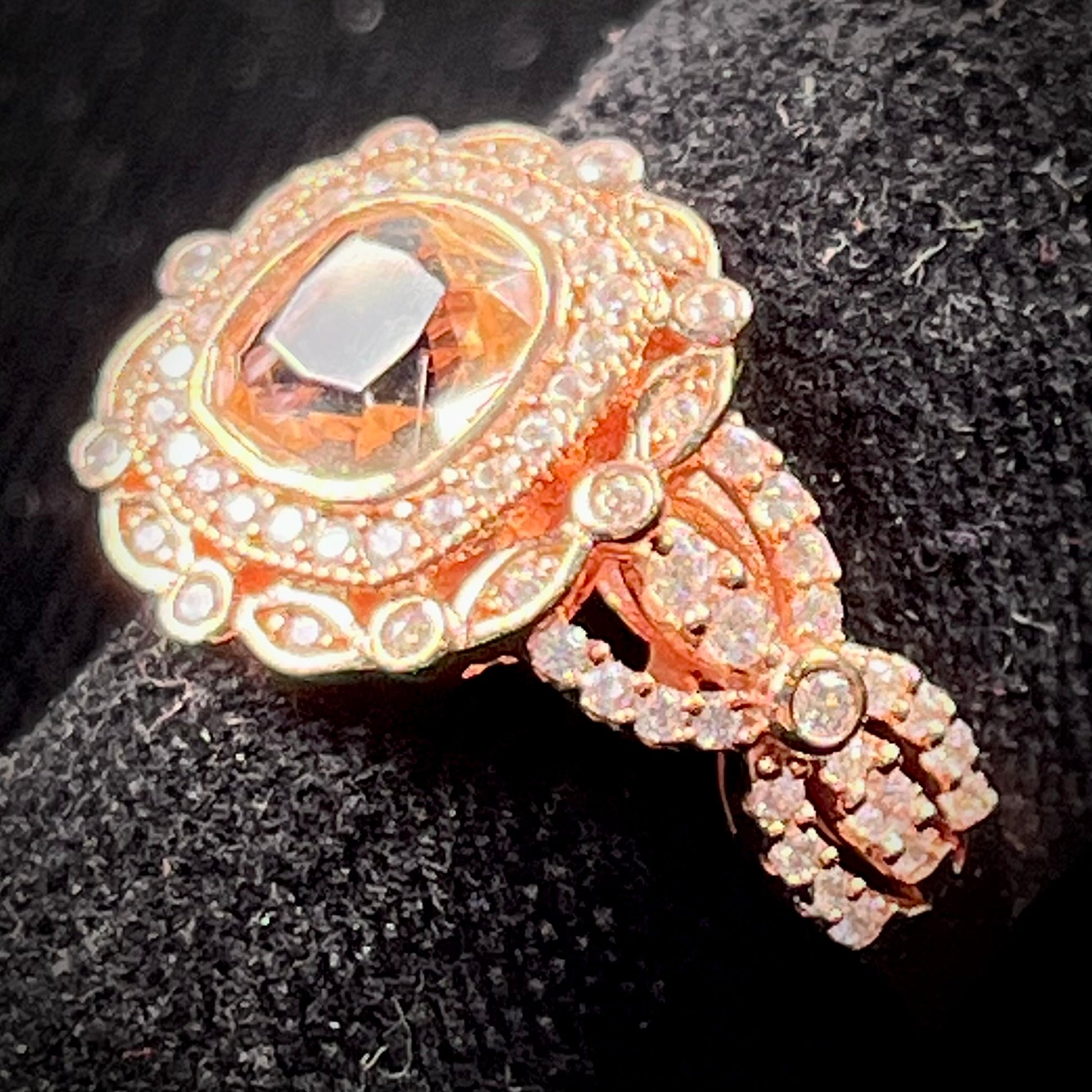 A rose gold plated ring set with a cushion cut morganite stone surrounded by cubic zirconia halos.