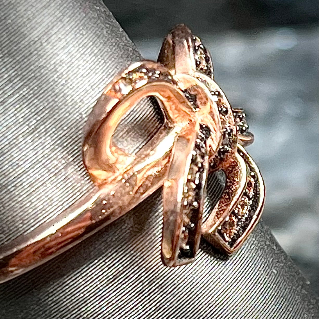 A rose gold colored bow ring.  The bow is tied in a knot, and the knot is set with cognac cubic zirconia.