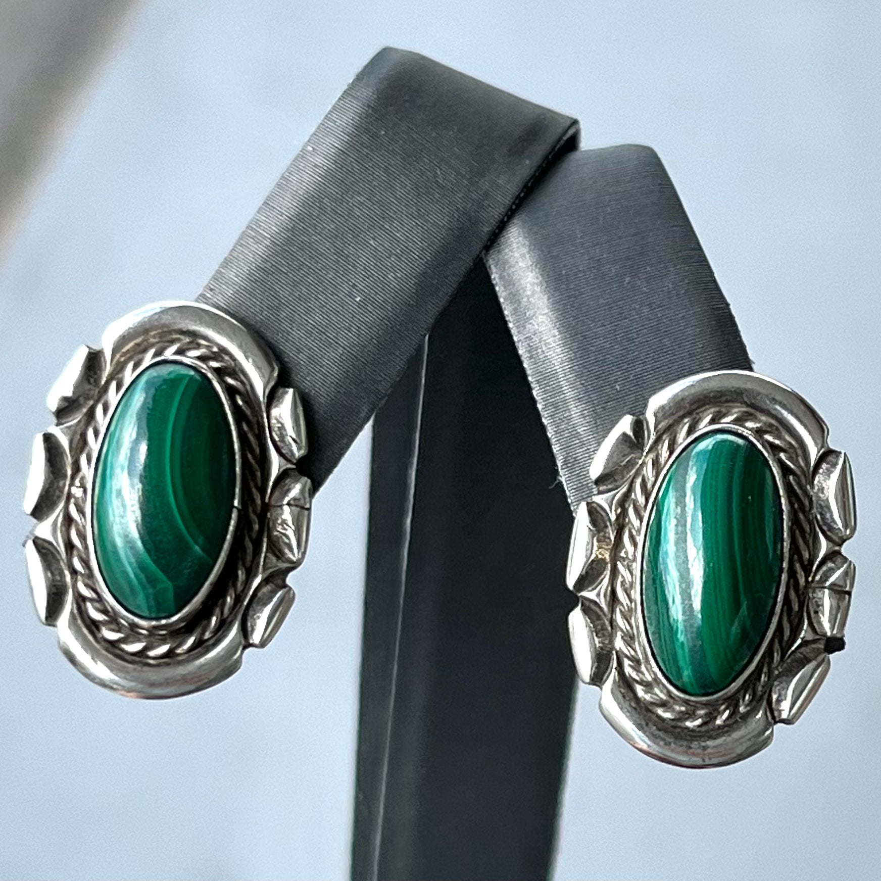 A pair of Southwest style post earrings set with oval cabochon cut malachite stones.