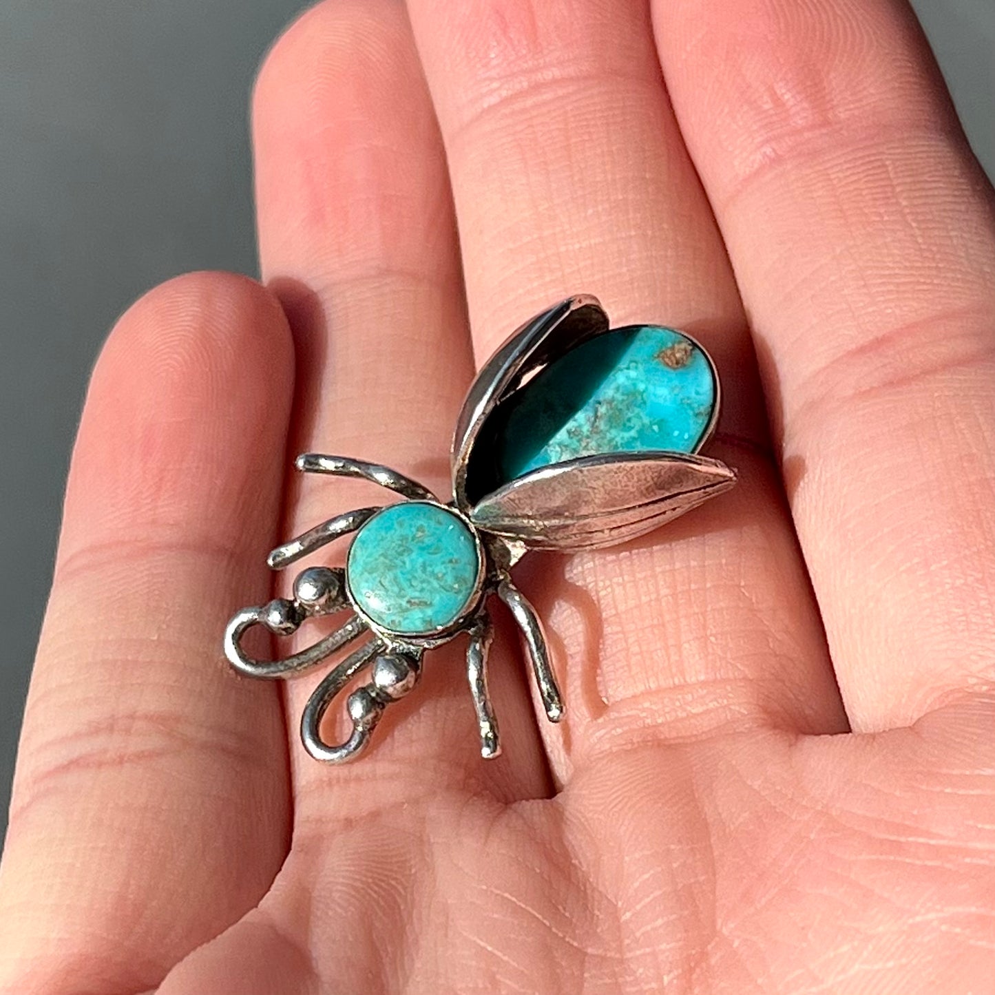 A sterling silver brooch made in the shape of a bee set with two turquoise stones for the head and body.