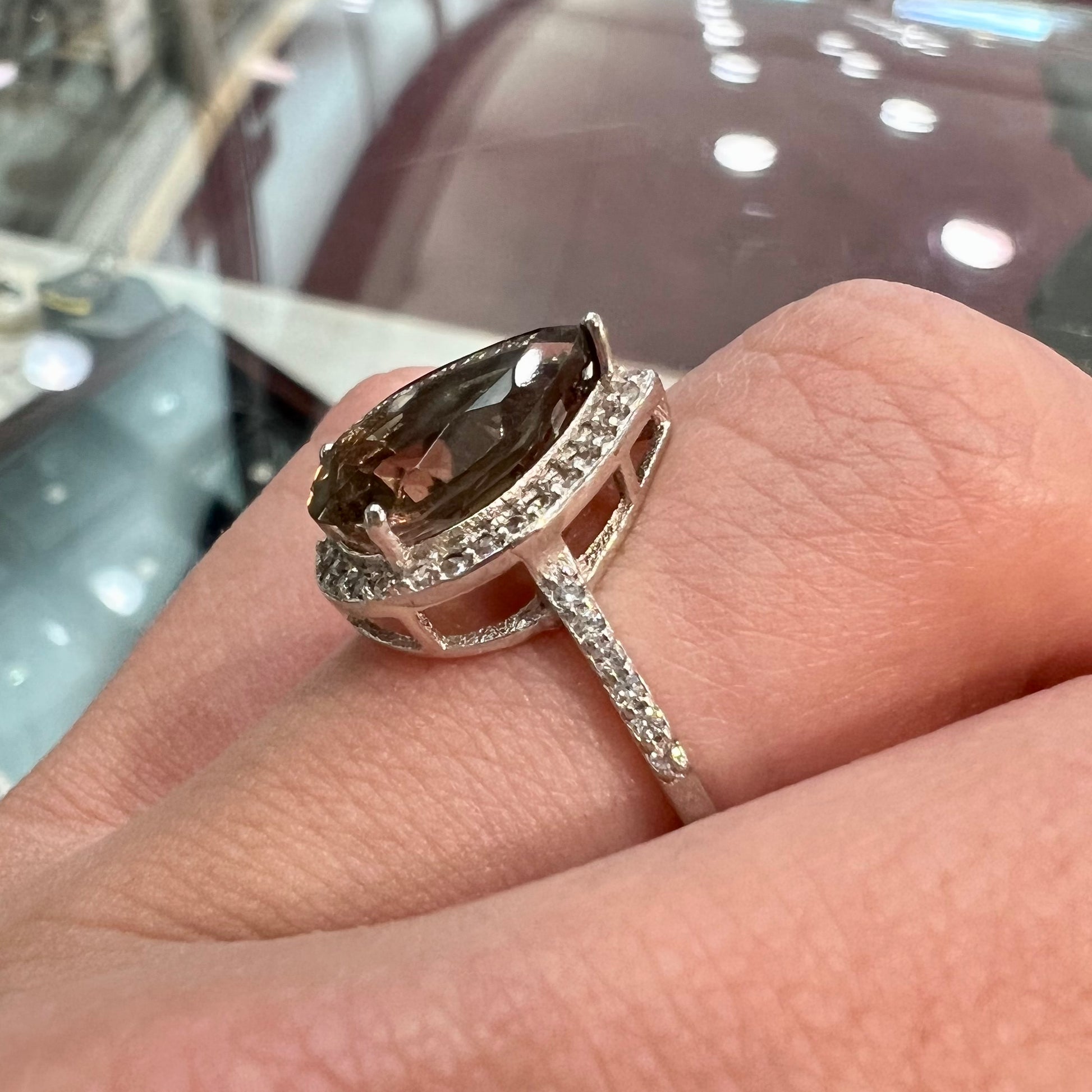 A pear shape smoky quartz set in a sterling silver and CZ halo ring.