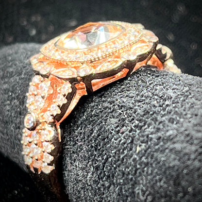 A rose gold plated ring set with a cushion cut morganite stone surrounded by cubic zirconia halos.