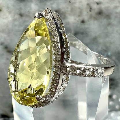 A pear shape lemon quartz set in a sterling silver and white topaz halo ring.