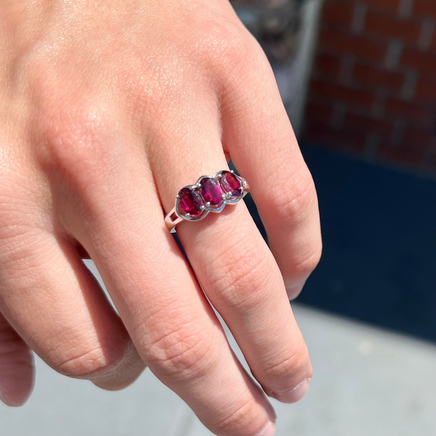 A three stone past, present, and future purple faceted oval cut rhodolite garnet ring.