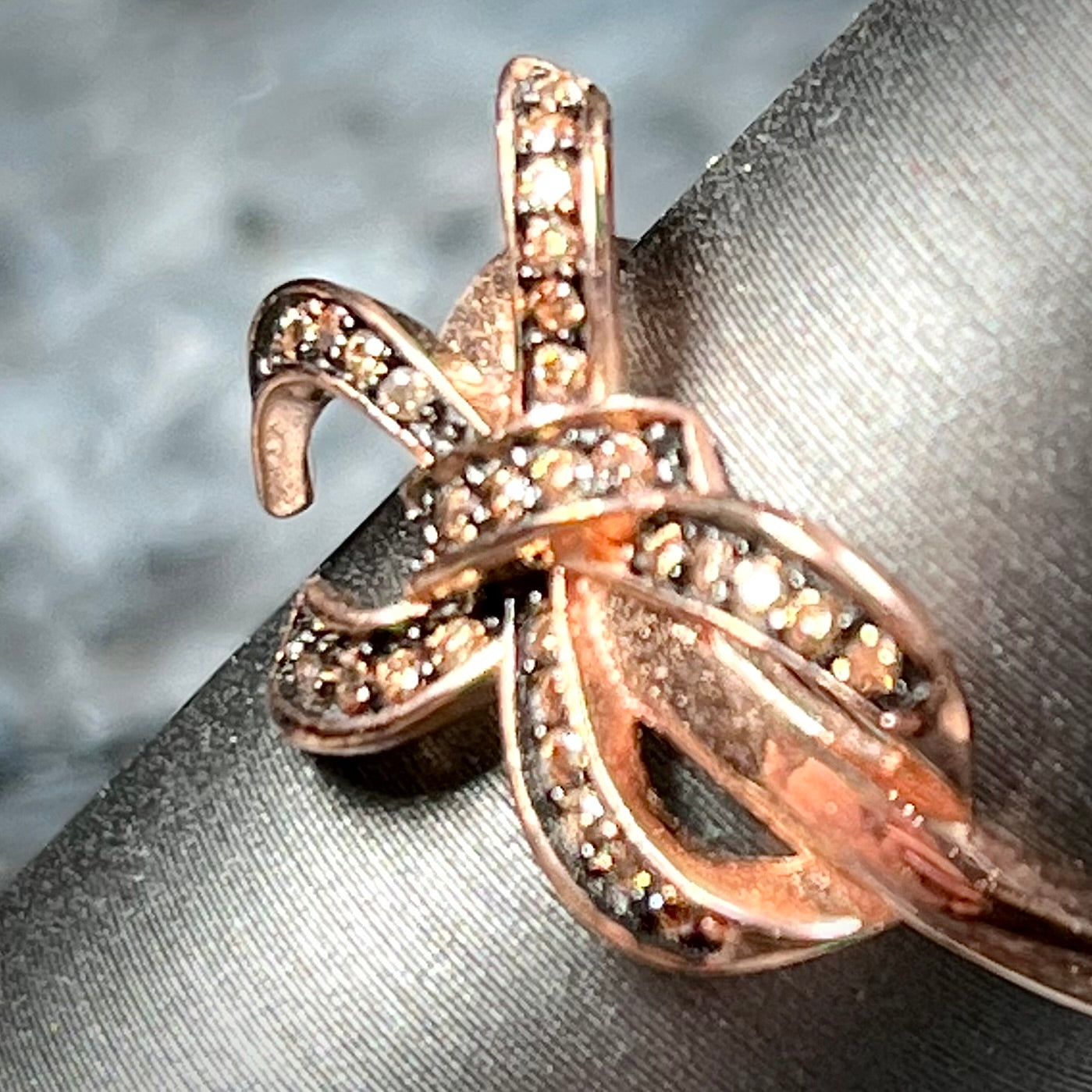 A rose gold colored bow ring.  The bow is tied in a knot, and the knot is set with cognac cubic zirconia.
