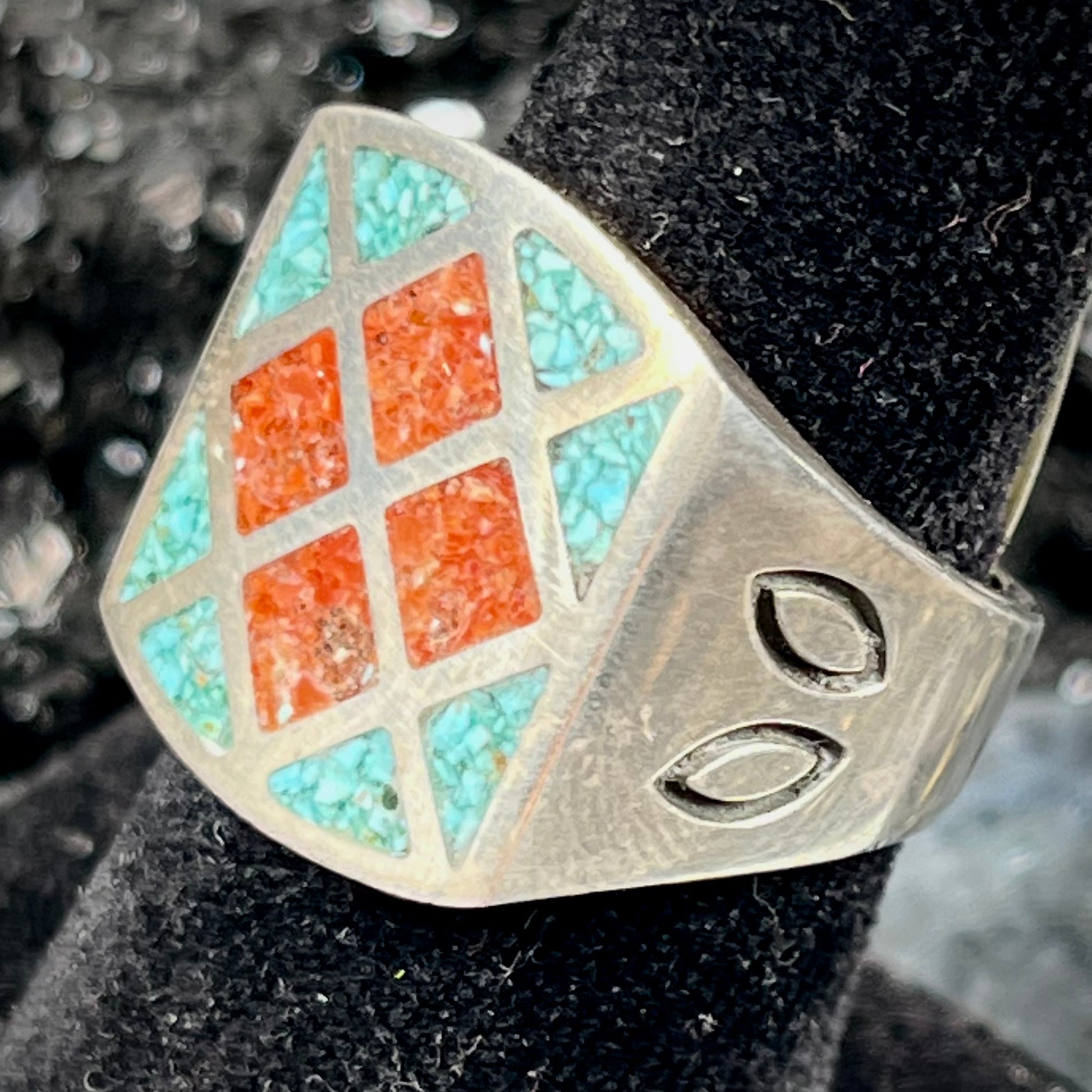 A men's sterling silver inlay ring set with sections of crushed blue turquoise and crushed red coral.