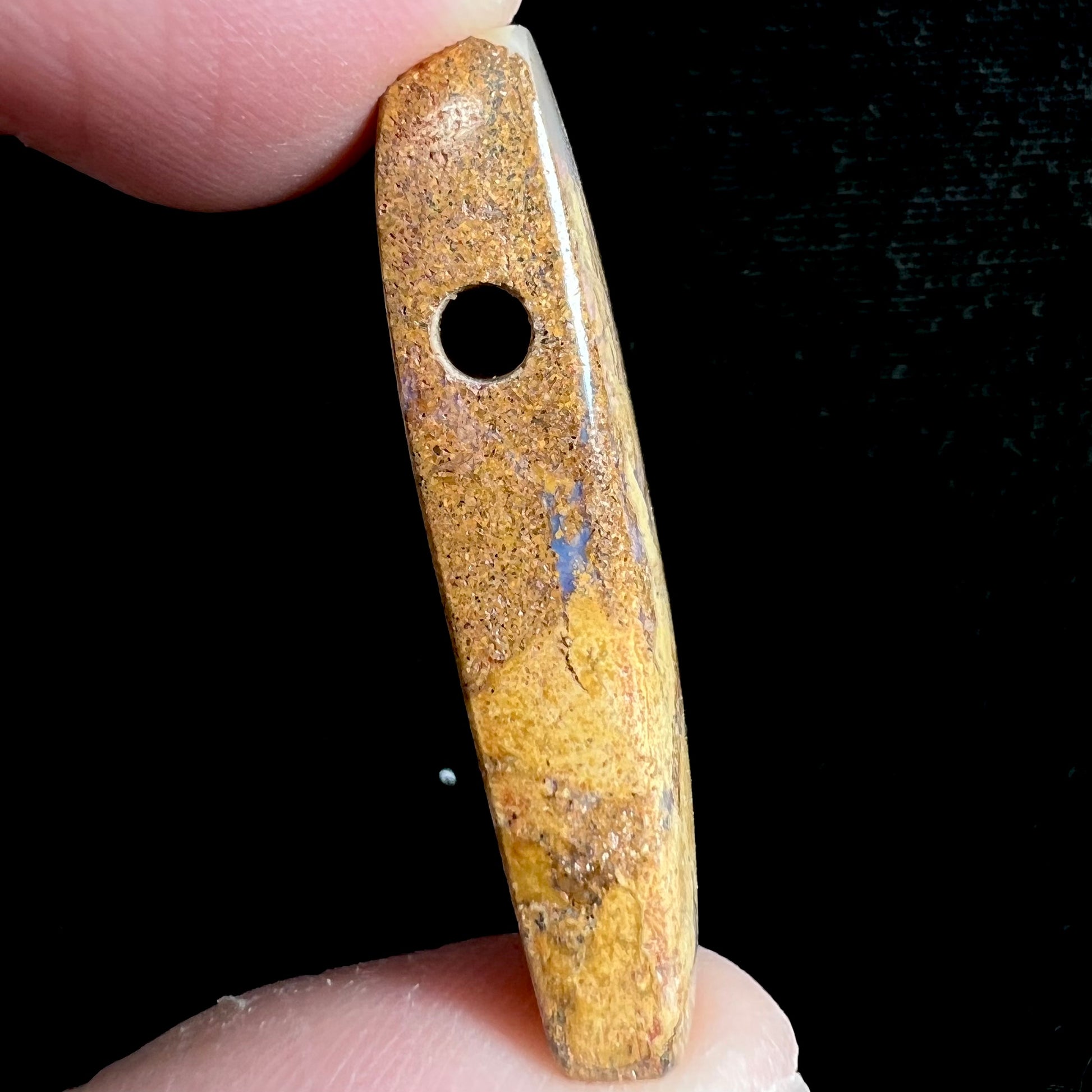 A polished, drilled pipe boulder opal bead.