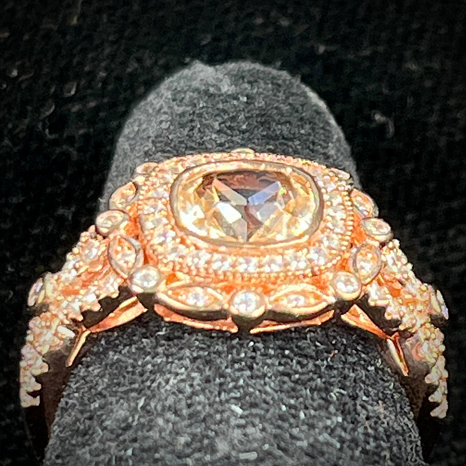 A rose gold plated ring set with a cushion cut morganite stone surrounded by cubic zirconia halos.