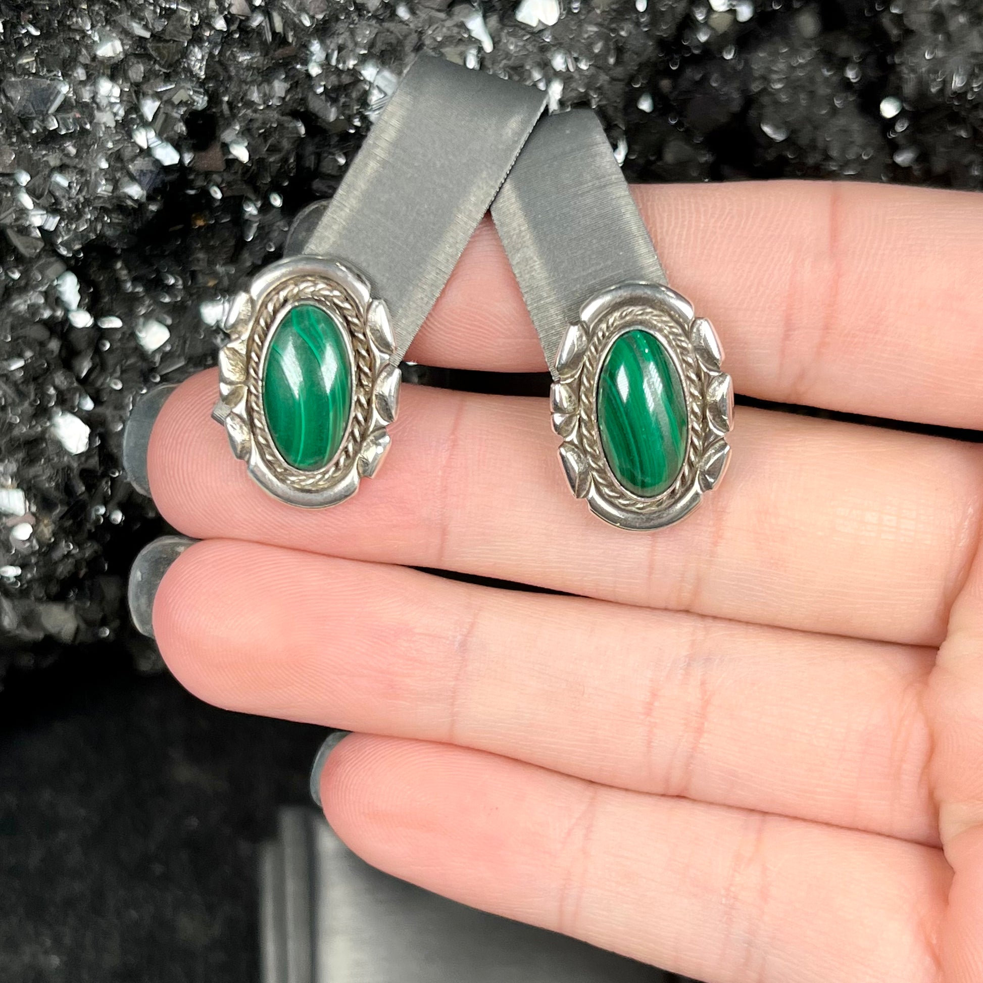 A pair of Southwest style post earrings set with oval cabochon cut malachite stones.