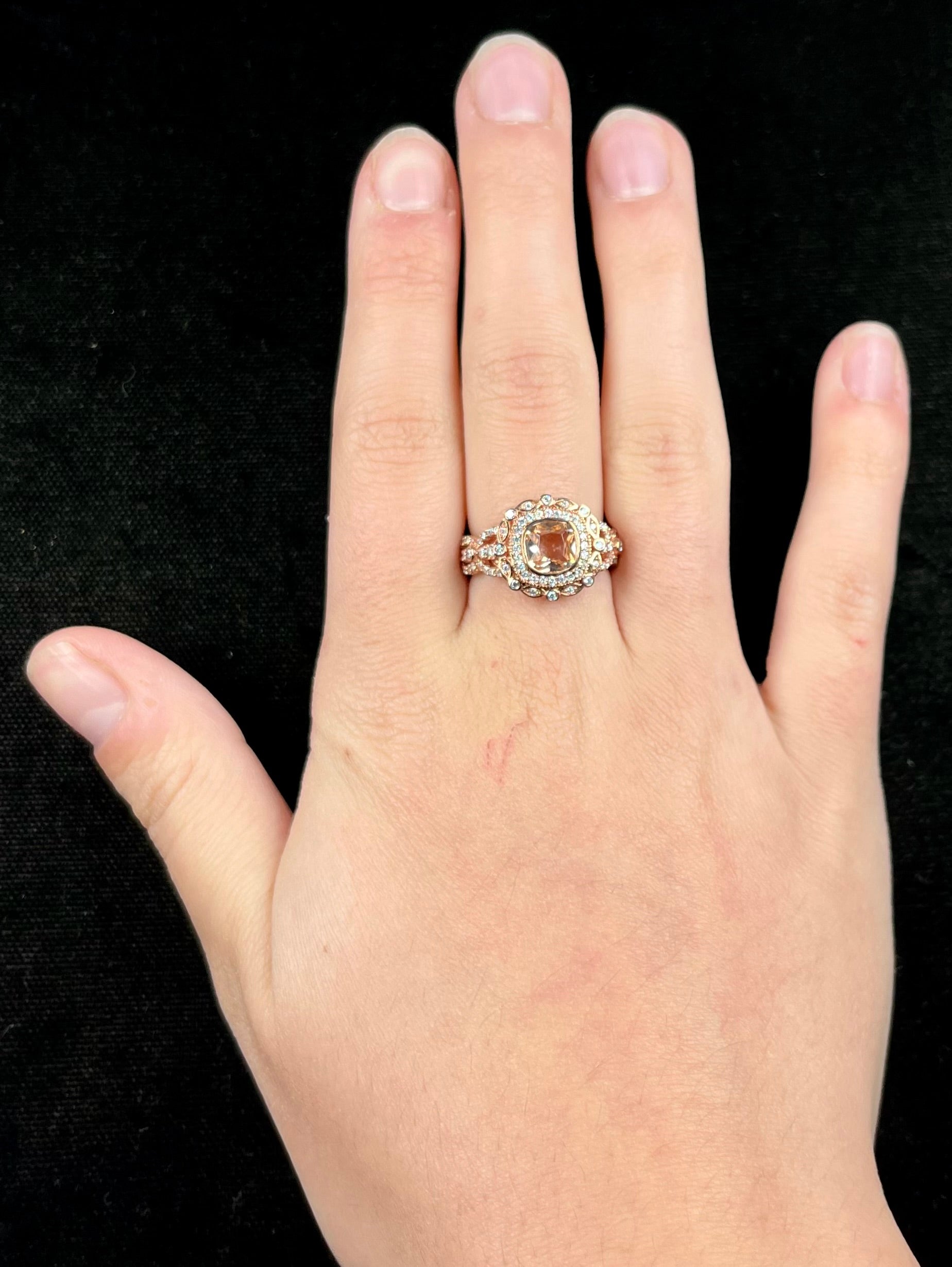A rose gold plated ring set with a cushion cut morganite stone surrounded by cubic zirconia halos.