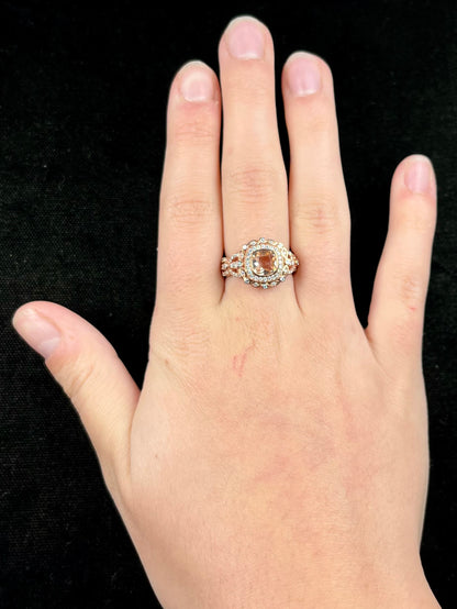 A rose gold plated ring set with a cushion cut morganite stone surrounded by cubic zirconia halos.