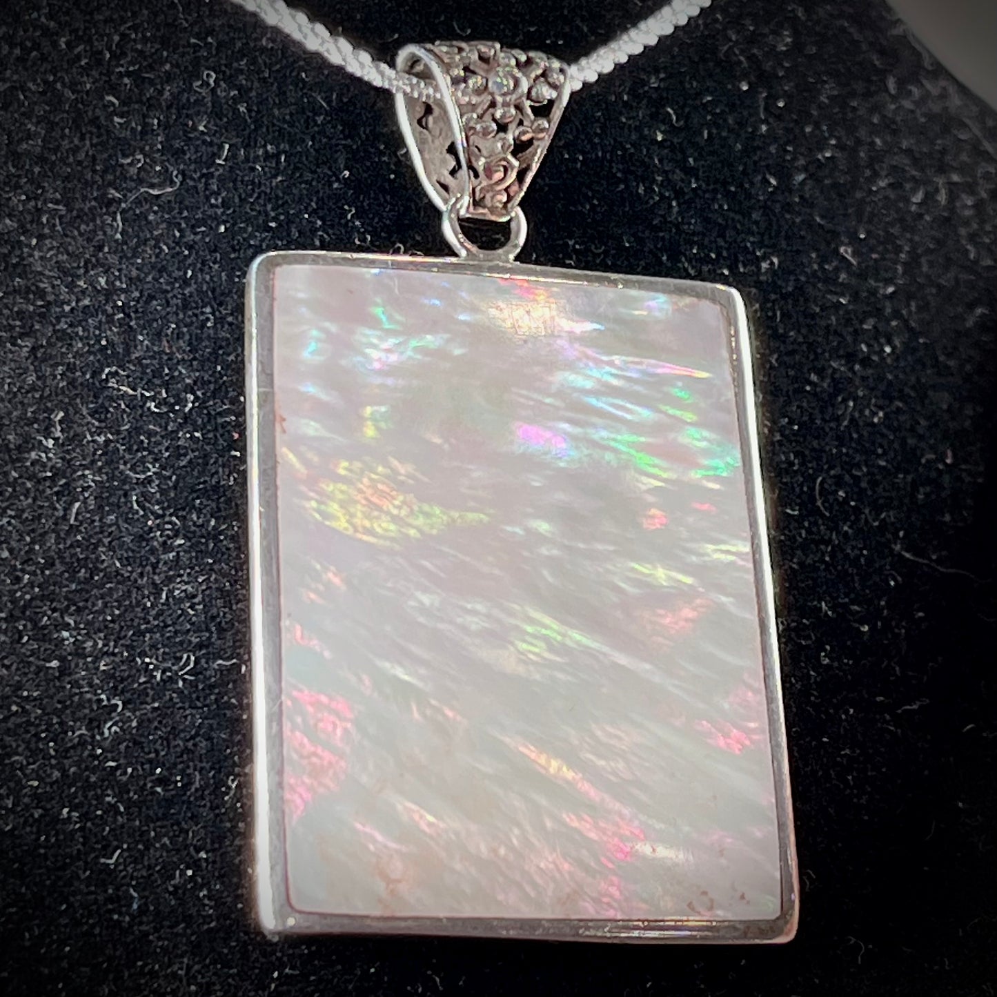 A sterling silver pendant set with rectangular slices of abalone shell and red fossil coral.