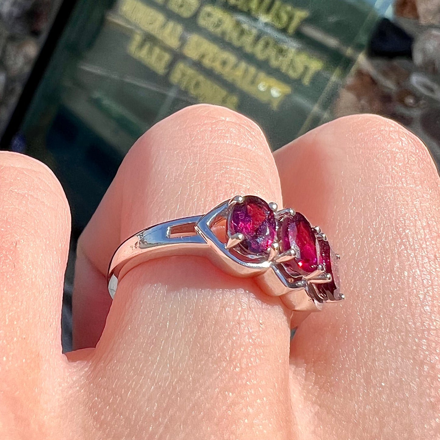 A three stone past, present, and future purple faceted oval cut rhodolite garnet ring.