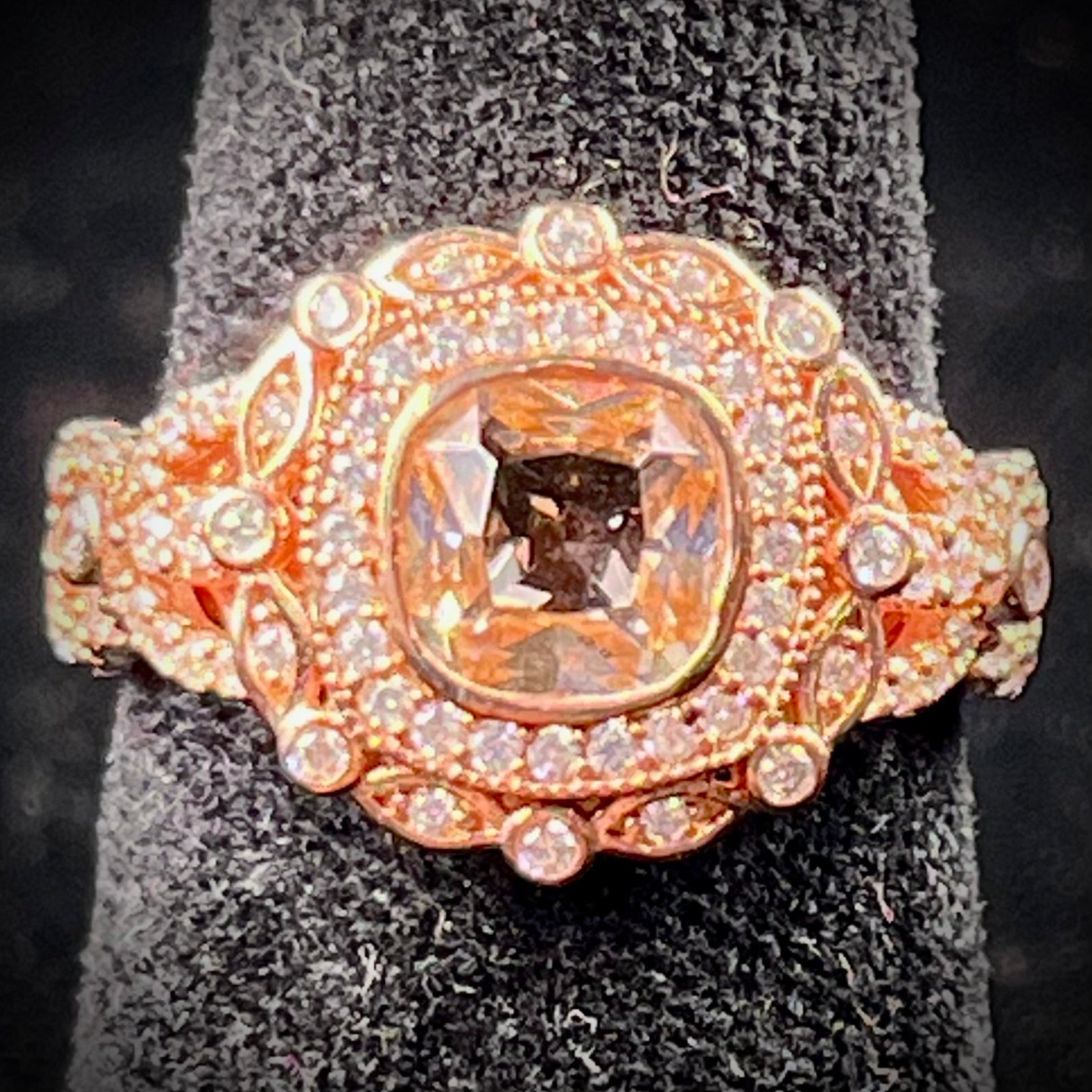 A rose gold plated ring set with a cushion cut morganite stone surrounded by cubic zirconia halos.