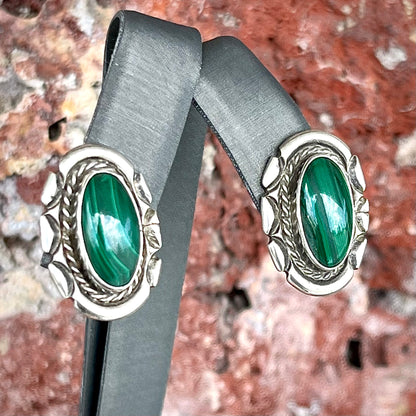 A pair of Southwest style post earrings set with oval cabochon cut malachite stones.