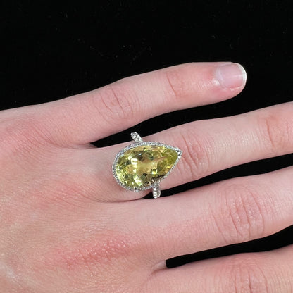 A pear shape lemon quartz set in a sterling silver and white topaz halo ring.