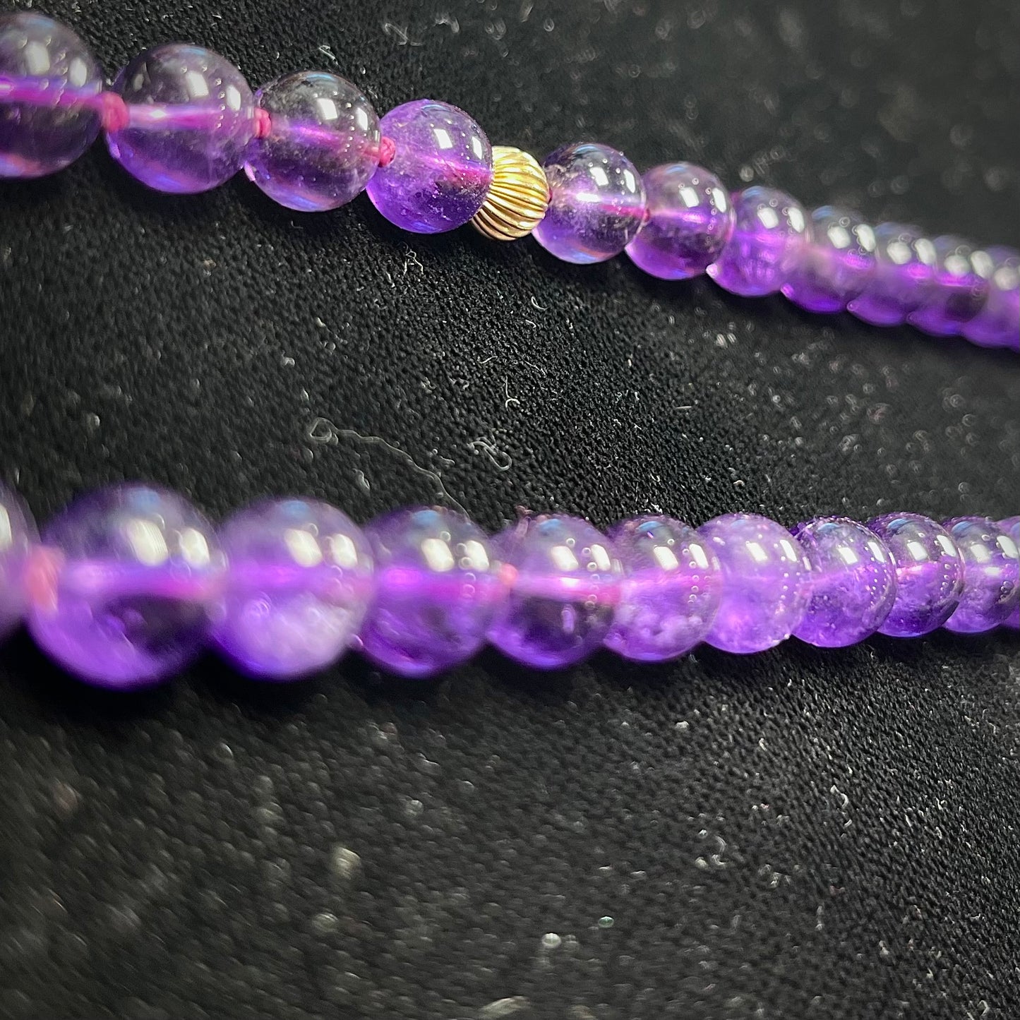 A beaded necklace made with round amethyst and 14k yellow gold beads.