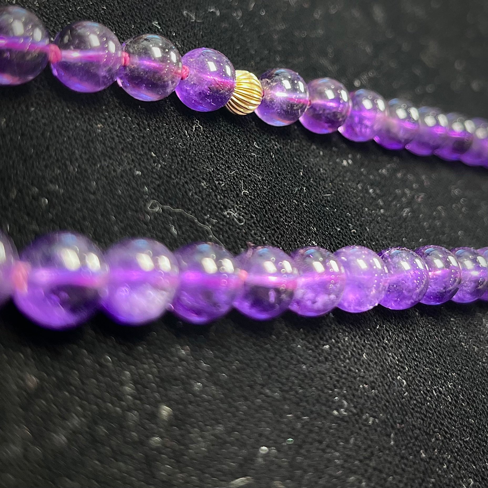 A beaded necklace made with round amethyst and 14k yellow gold beads.