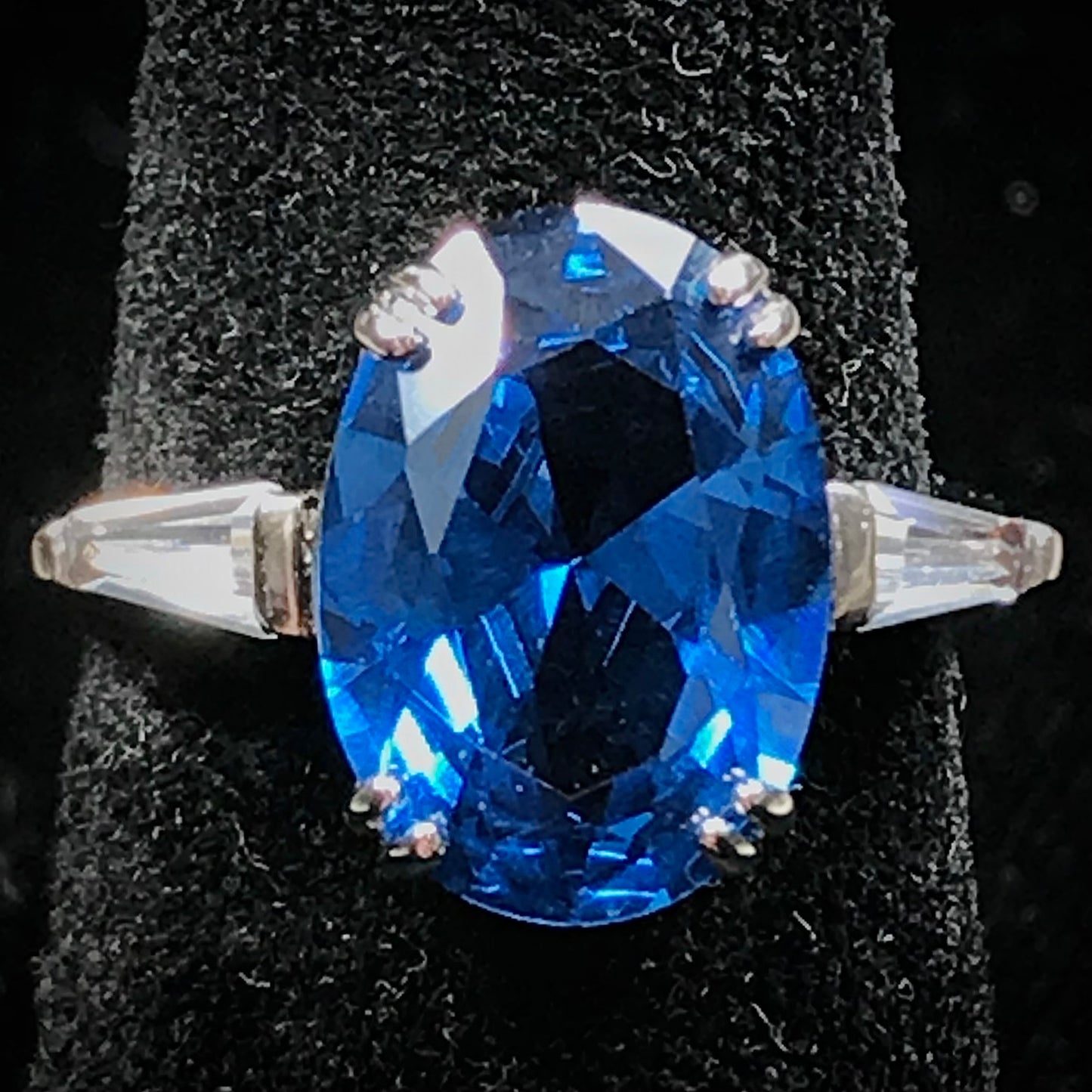 A sterling silver ring set with a faceted oval cut blue spinel and cubic zirconia baguettes.