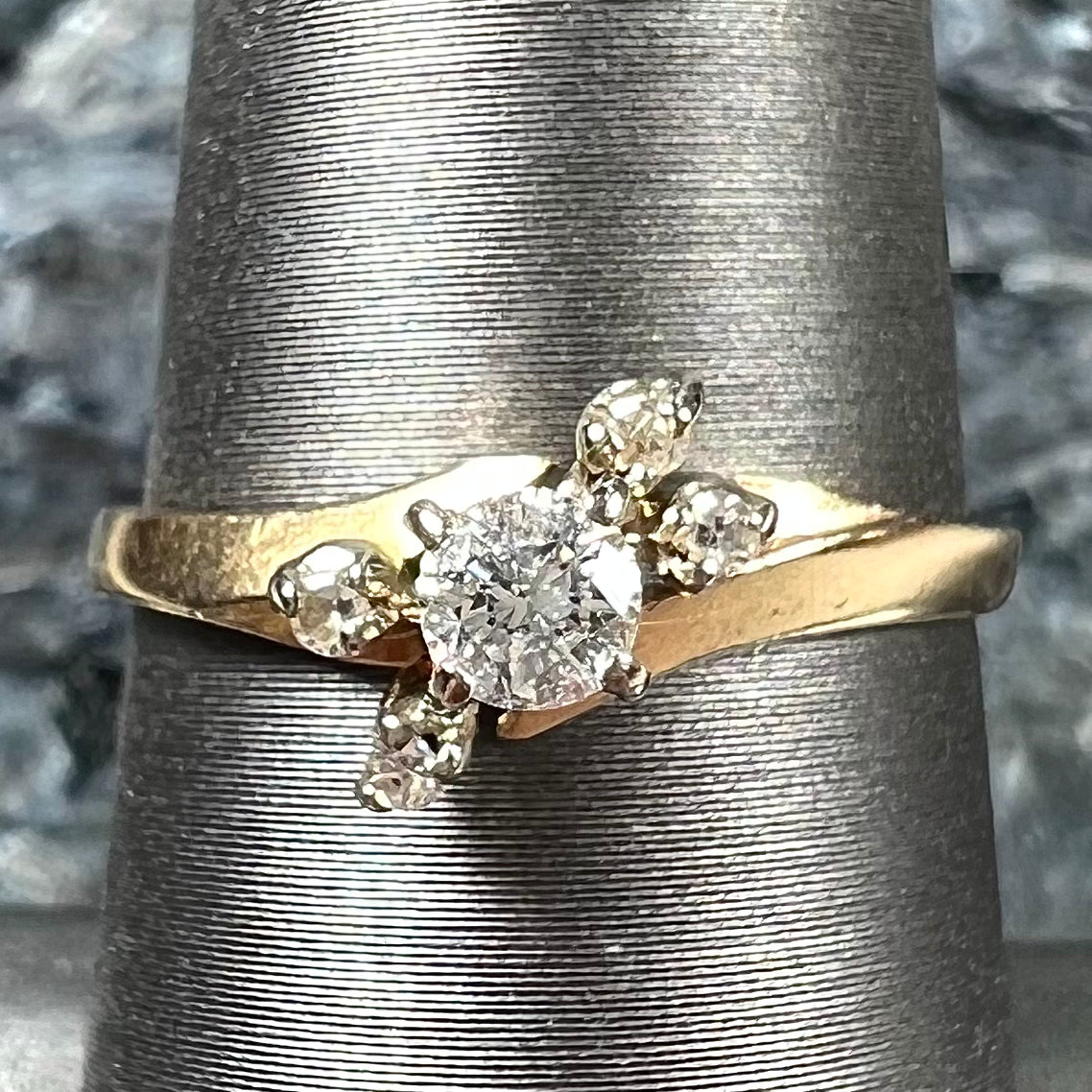 A yellow gold high-set diamond ring with four side diamonds.