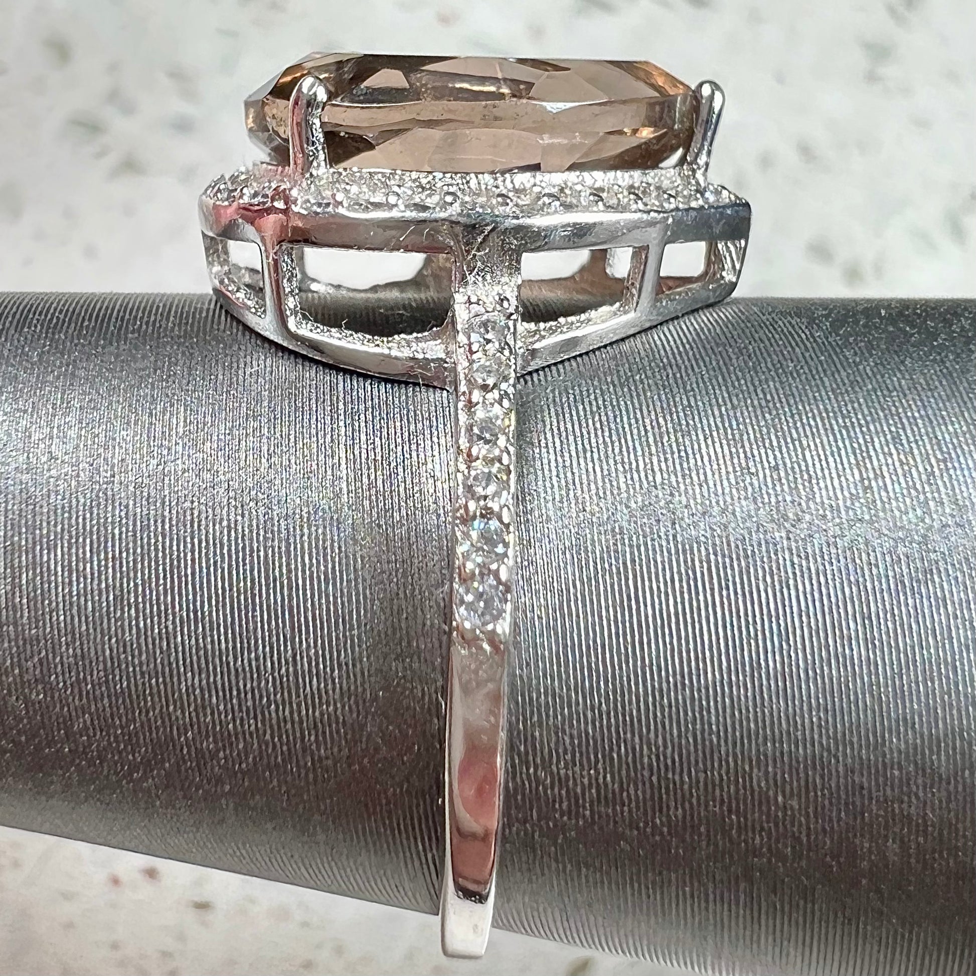 A pear shape smoky quartz set in a sterling silver and CZ halo ring.