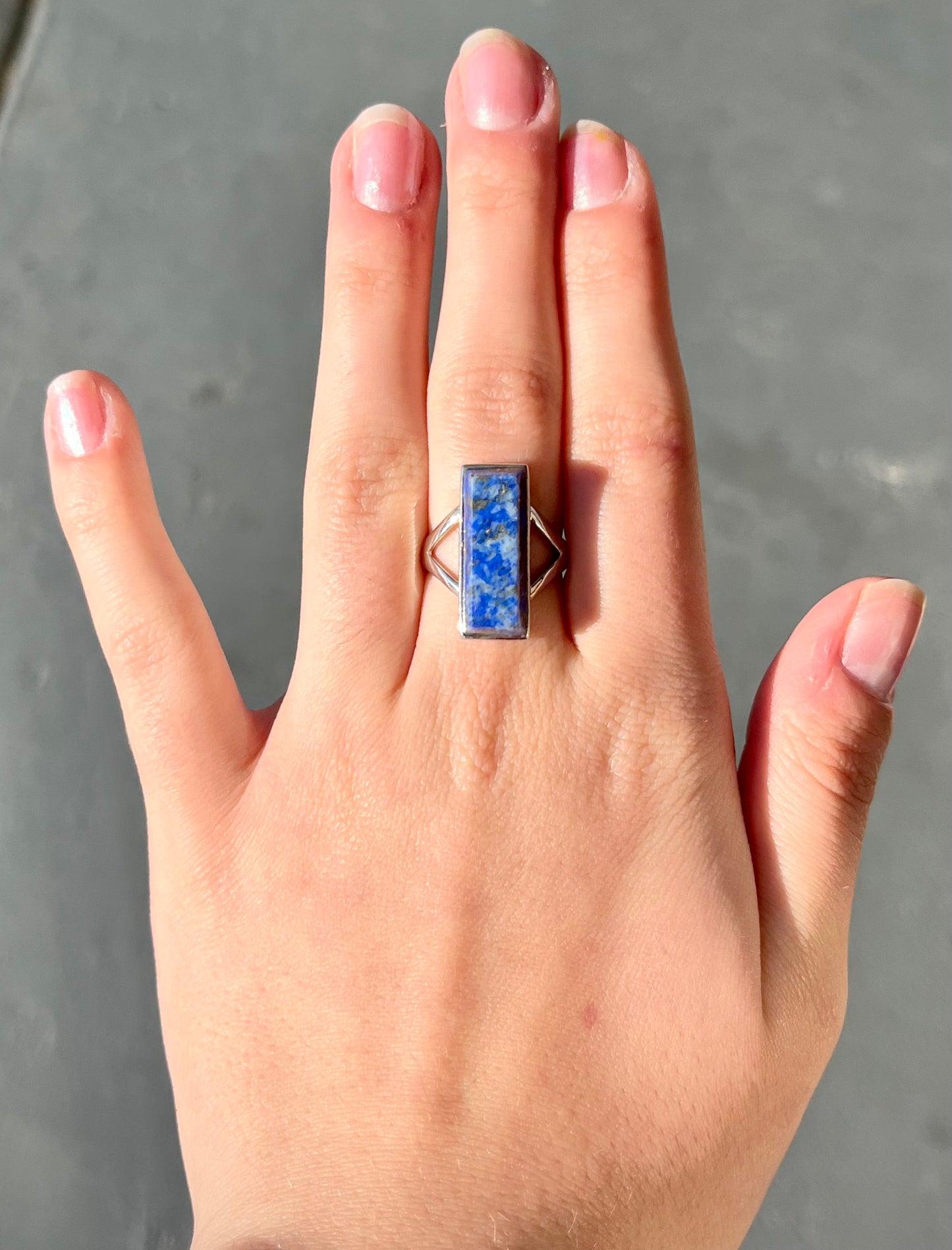 A split shank silver rectangular cabochon cut lapis lazuli ring.