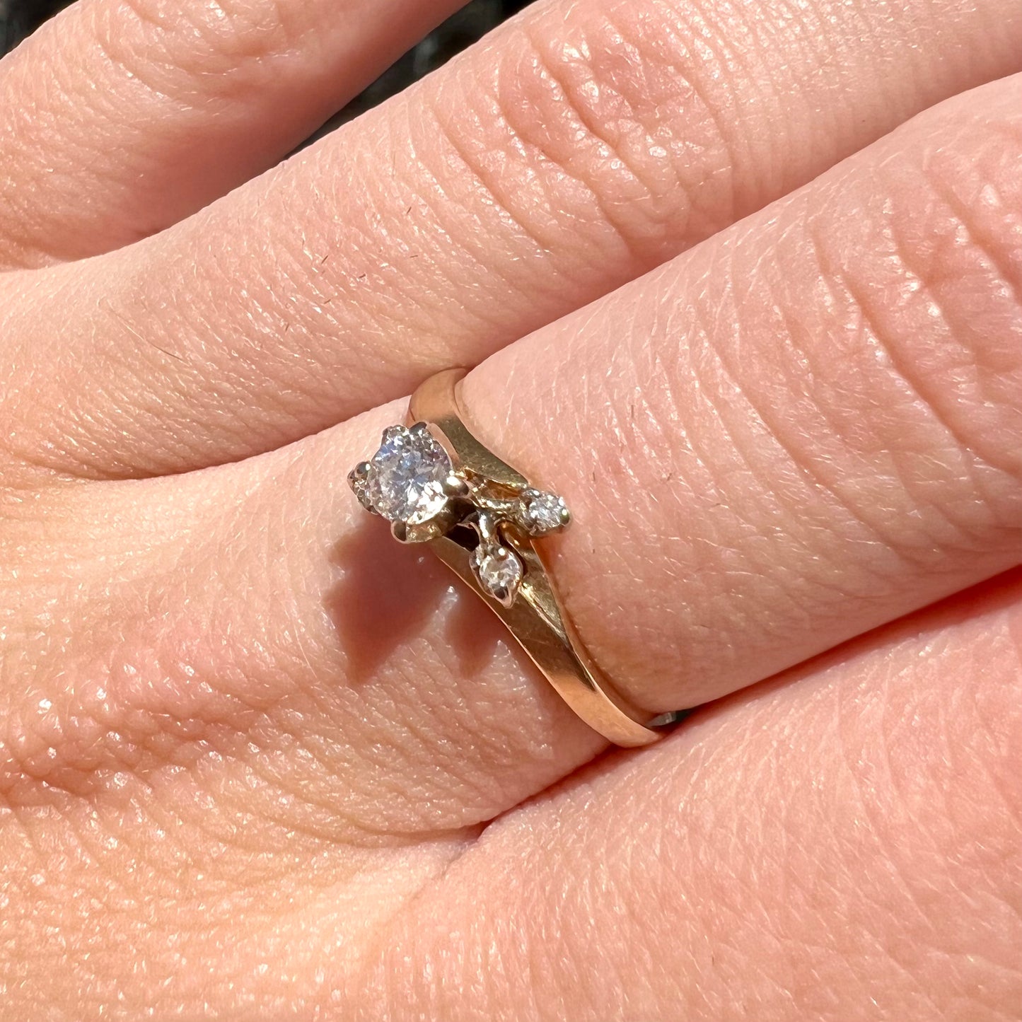 A yellow gold high-set diamond ring with four side diamonds.