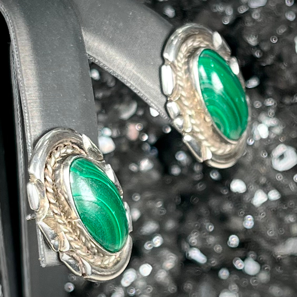 A pair of Southwest style post earrings set with oval cabochon cut malachite stones.