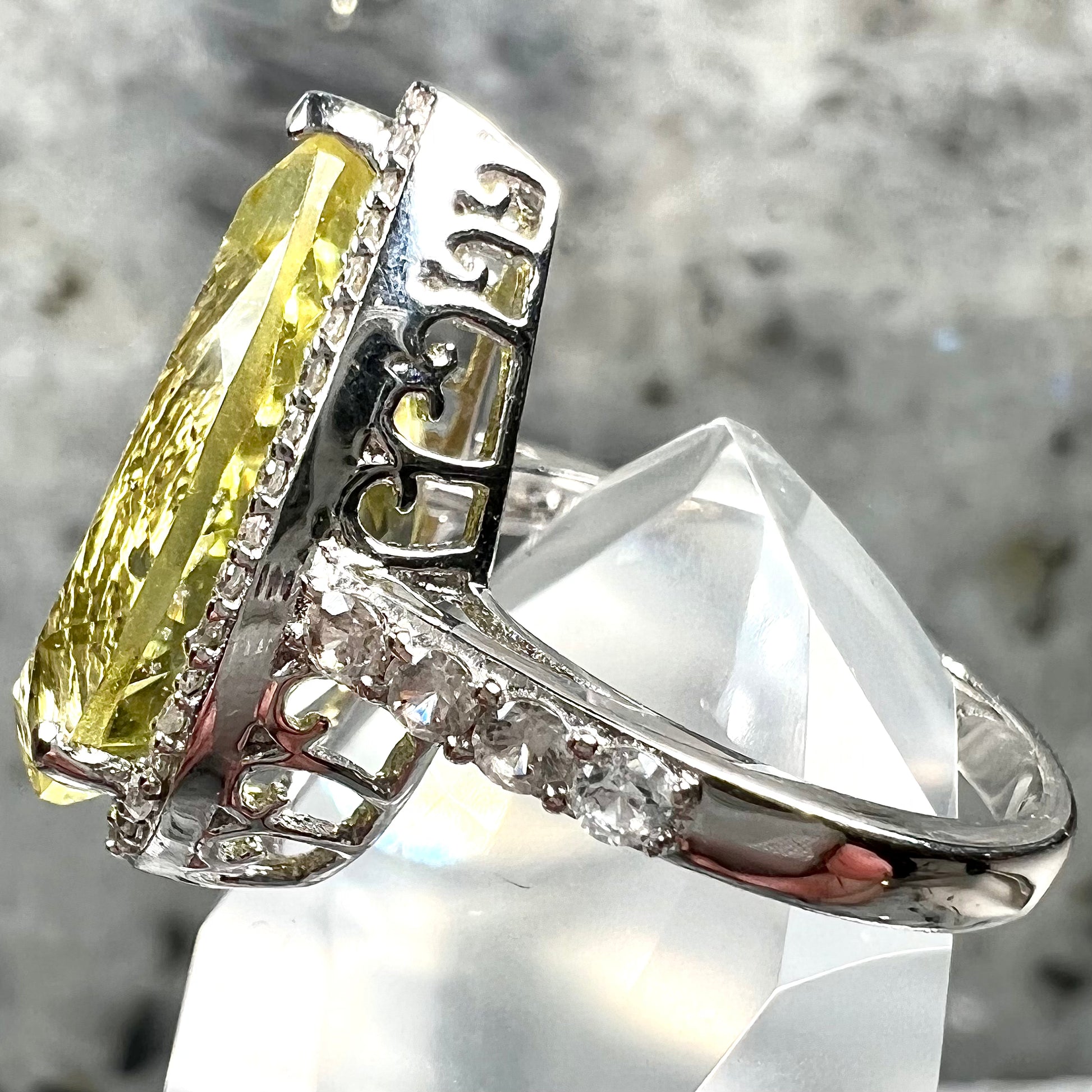 A pear shape lemon quartz set in a sterling silver and white topaz halo ring.