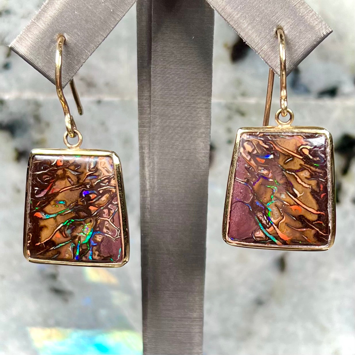 A pair of yellow gold French wire dangle earrings set with Koroit boulder opal.