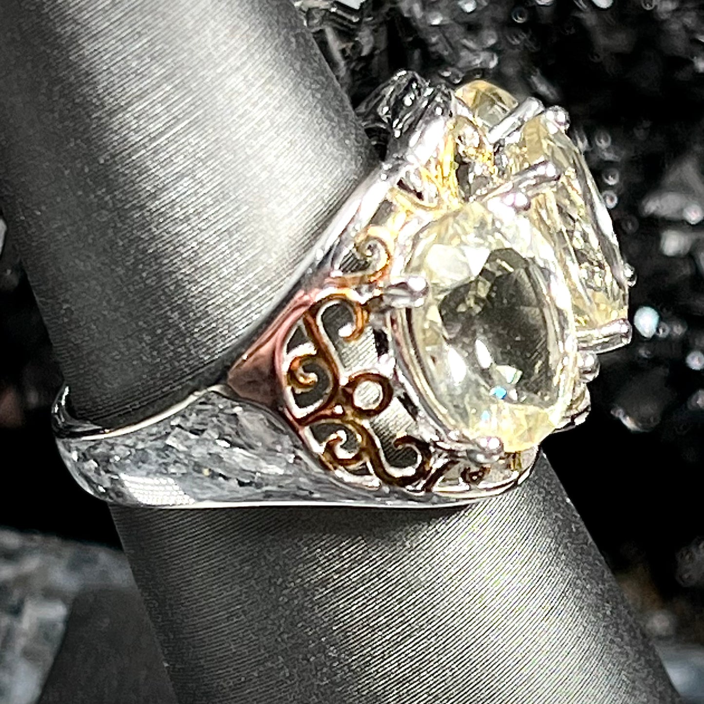 A sterling silver ring set with three oval cut golden beryl stones and yellow gold plated filigree accents.