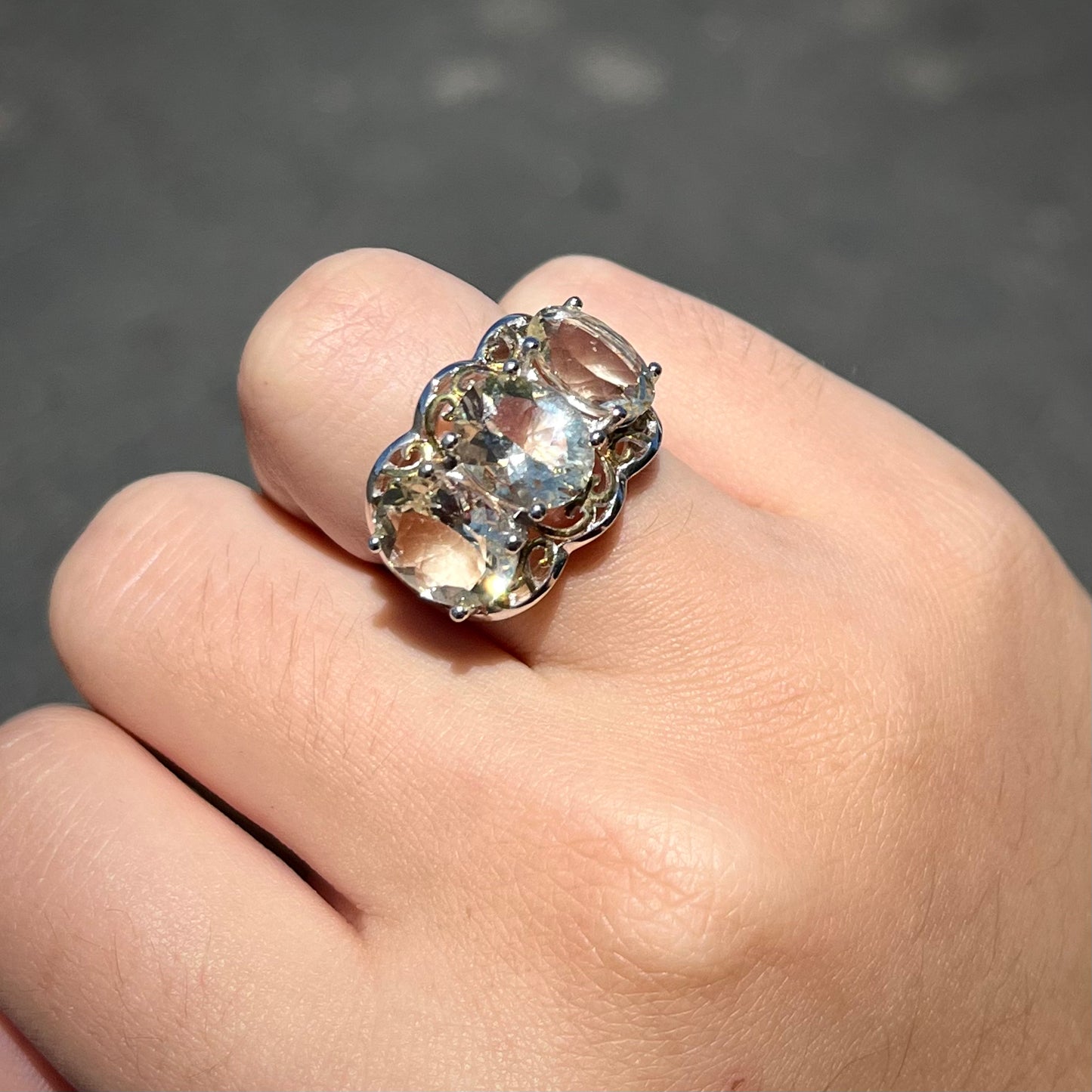 A sterling silver ring set with three oval cut golden beryl stones and yellow gold plated filigree accents.