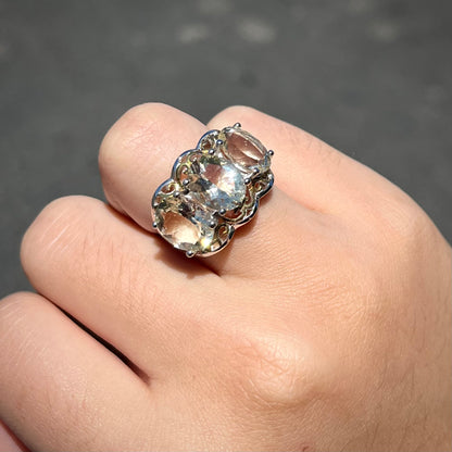 A sterling silver ring set with three oval cut golden beryl stones and yellow gold plated filigree accents.