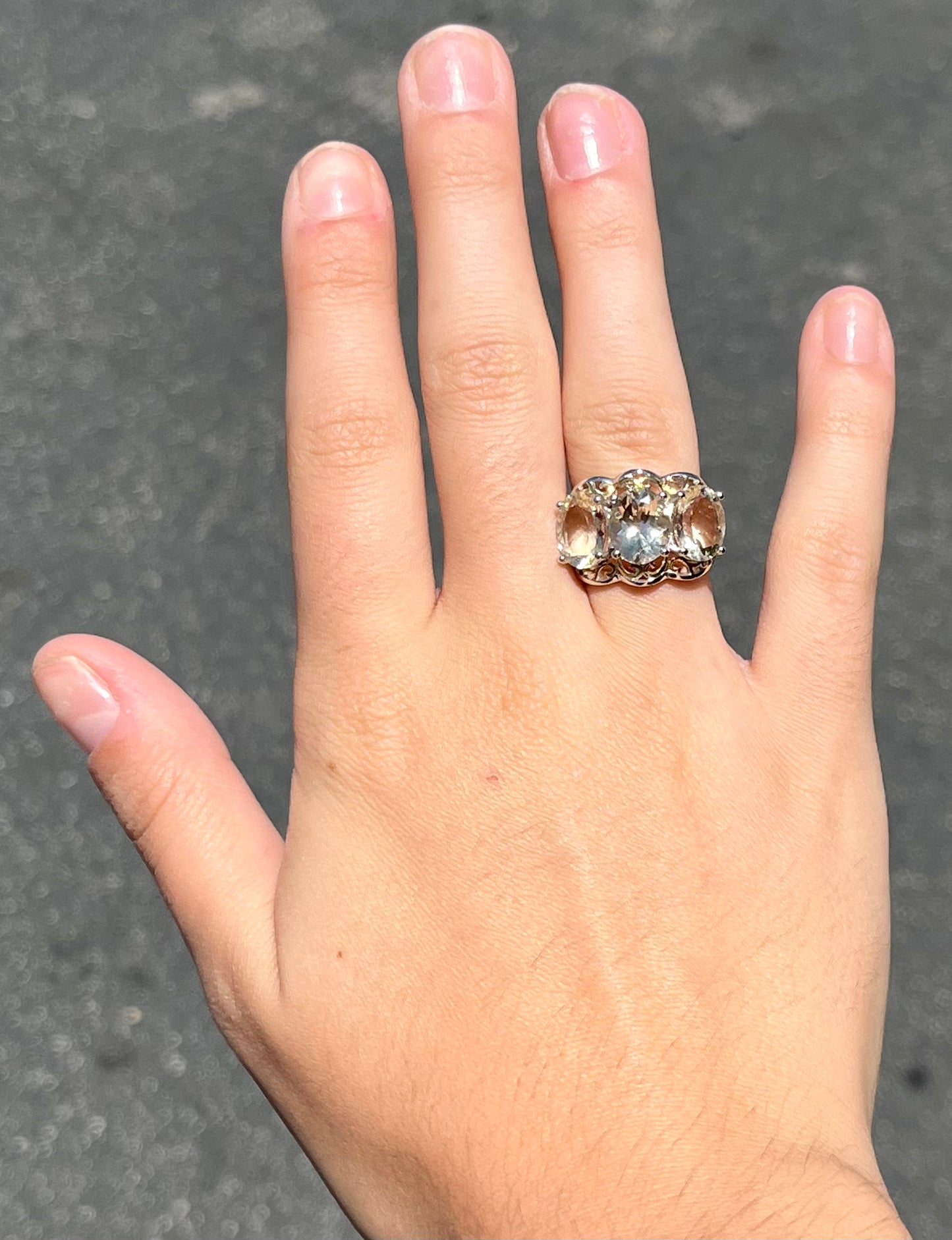 A sterling silver ring set with three oval cut golden beryl stones and yellow gold plated filigree accents.