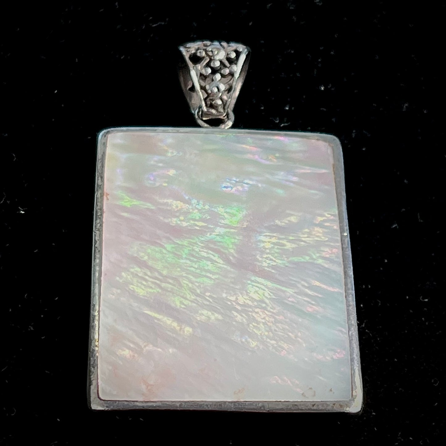 A sterling silver pendant set with rectangular slices of abalone shell and red fossil coral.