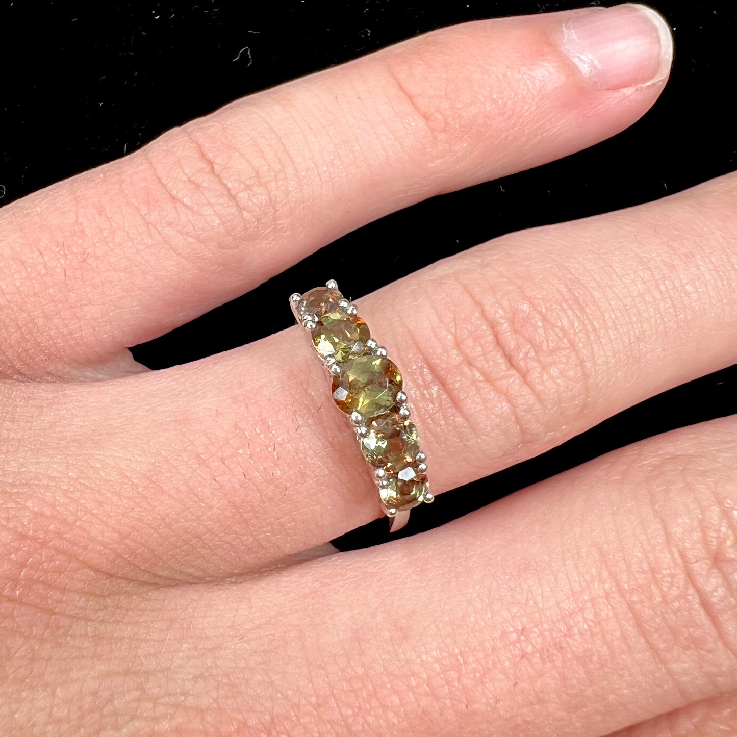 A sterling silver stackable ring set with five faceted oval and round andalusite stones.