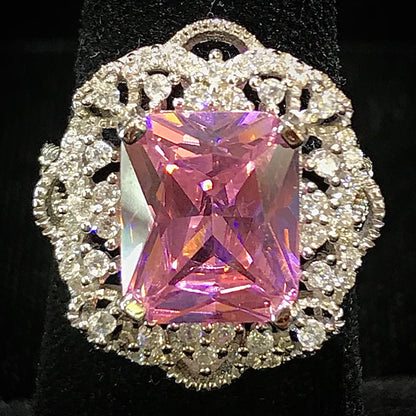An ornate silver ring set with a cushion cut pink cubic zirconia stone.