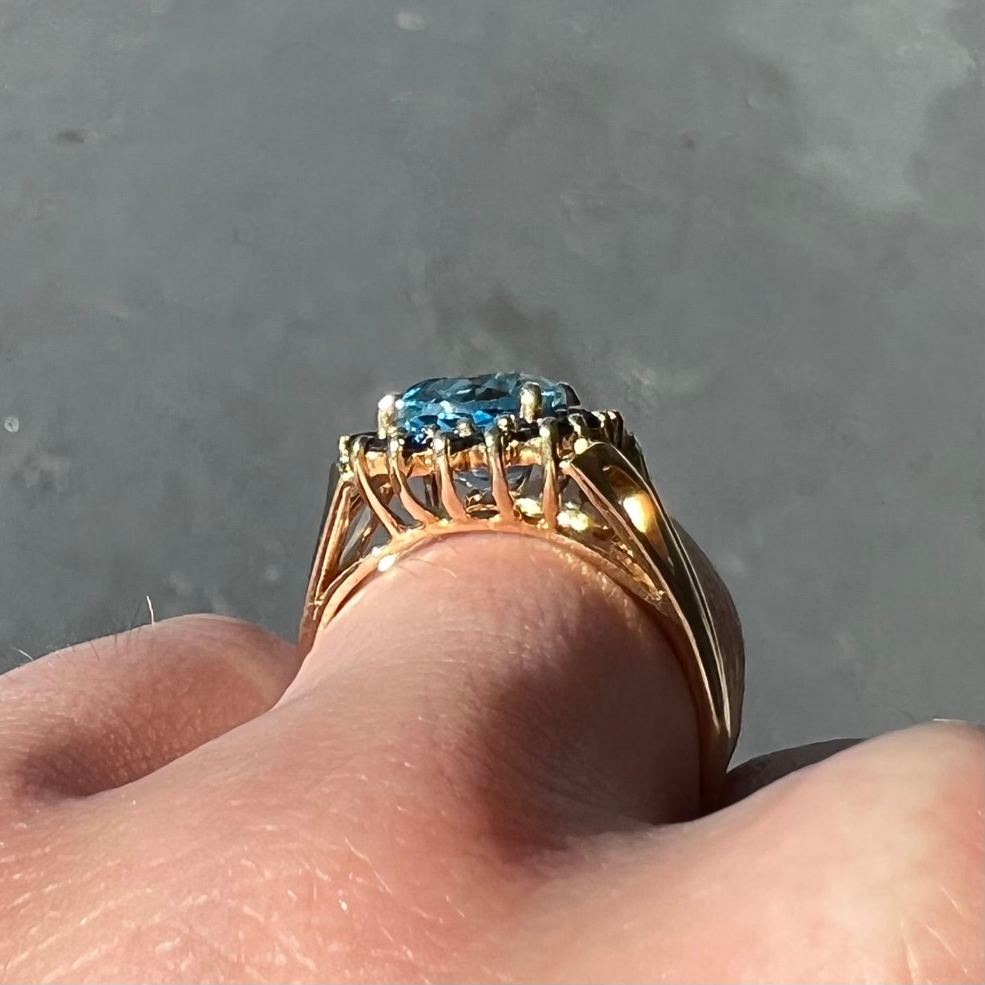 Yellow gold ring prong set with swiss blue topaz center stone and a halo of blue round blue sapphires.