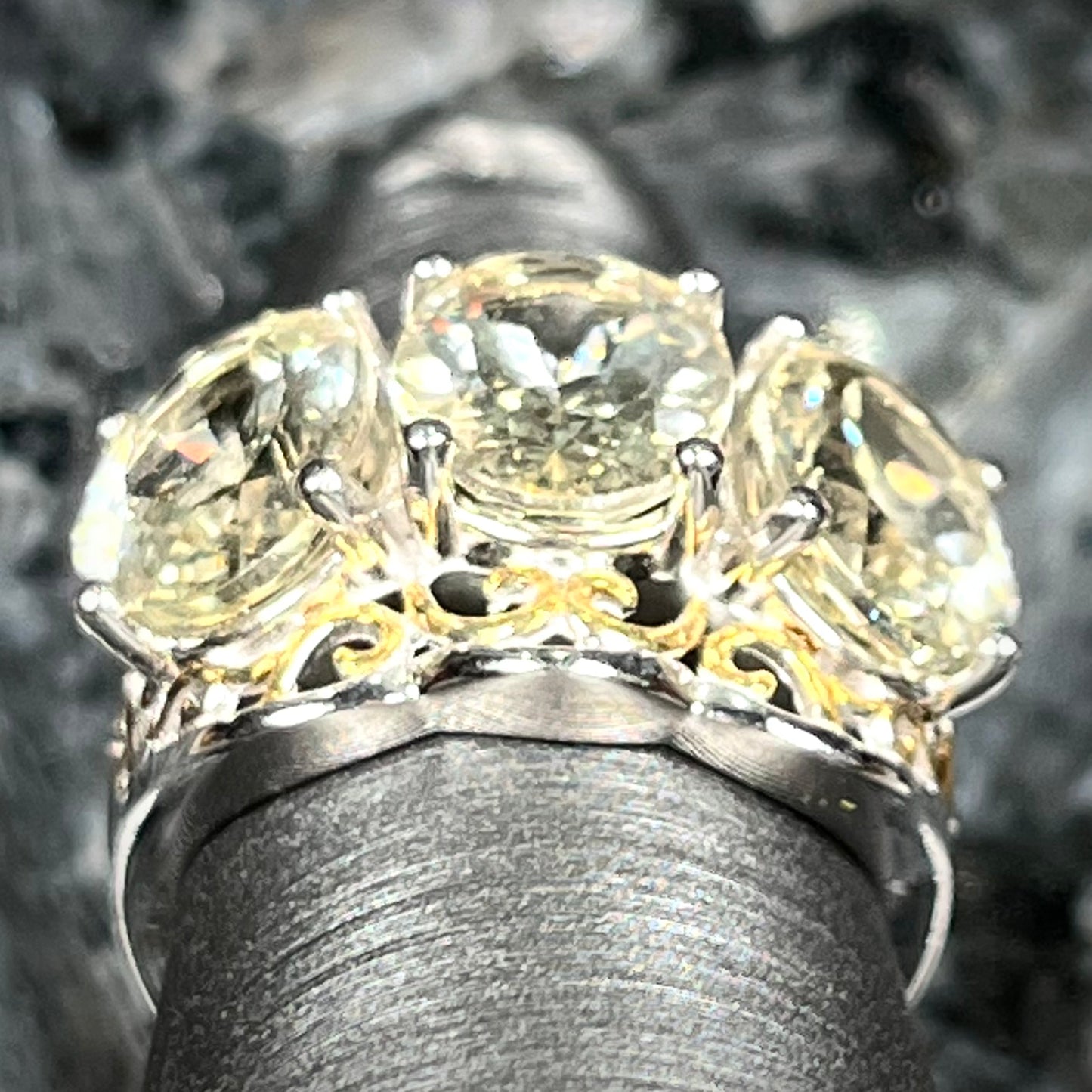 A sterling silver ring set with three oval cut golden beryl stones and yellow gold plated filigree accents.