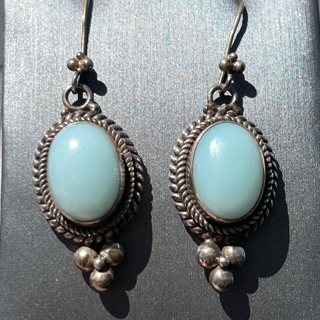 A pair of silver wire dangle earrings set with blue agate stones.  The earrings have a braided rope design.