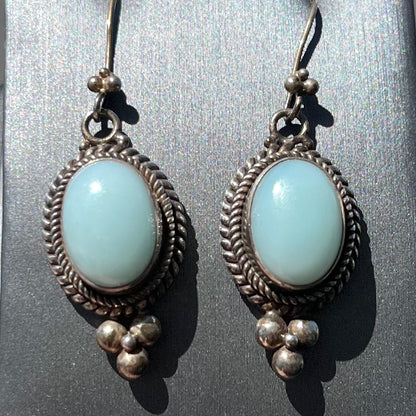 A pair of silver wire dangle earrings set with blue agate stones.  The earrings have a braided rope design.