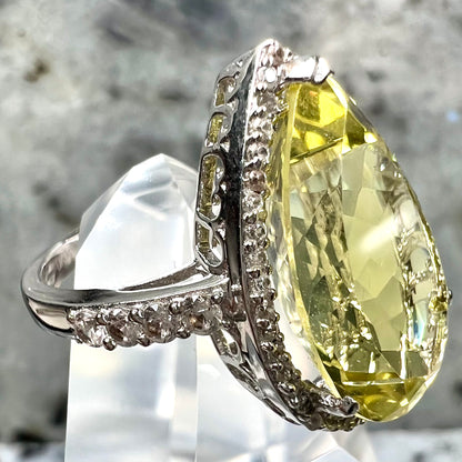 A pear shape lemon quartz set in a sterling silver and white topaz halo ring.