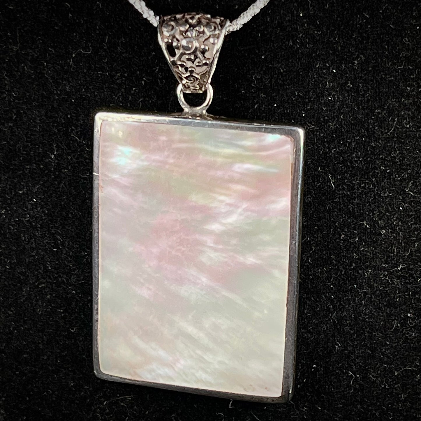 A sterling silver pendant set with rectangular slices of abalone shell and red fossil coral.