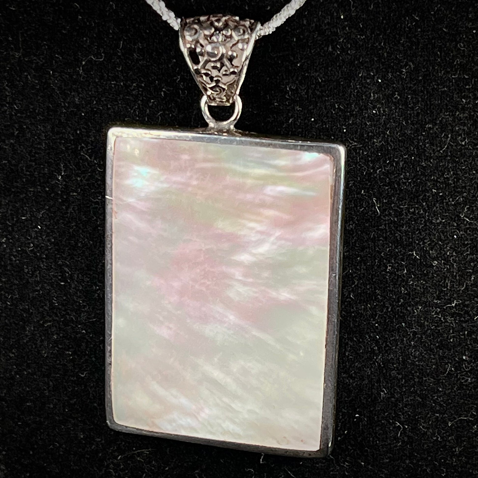 A sterling silver pendant set with rectangular slices of abalone shell and red fossil coral.