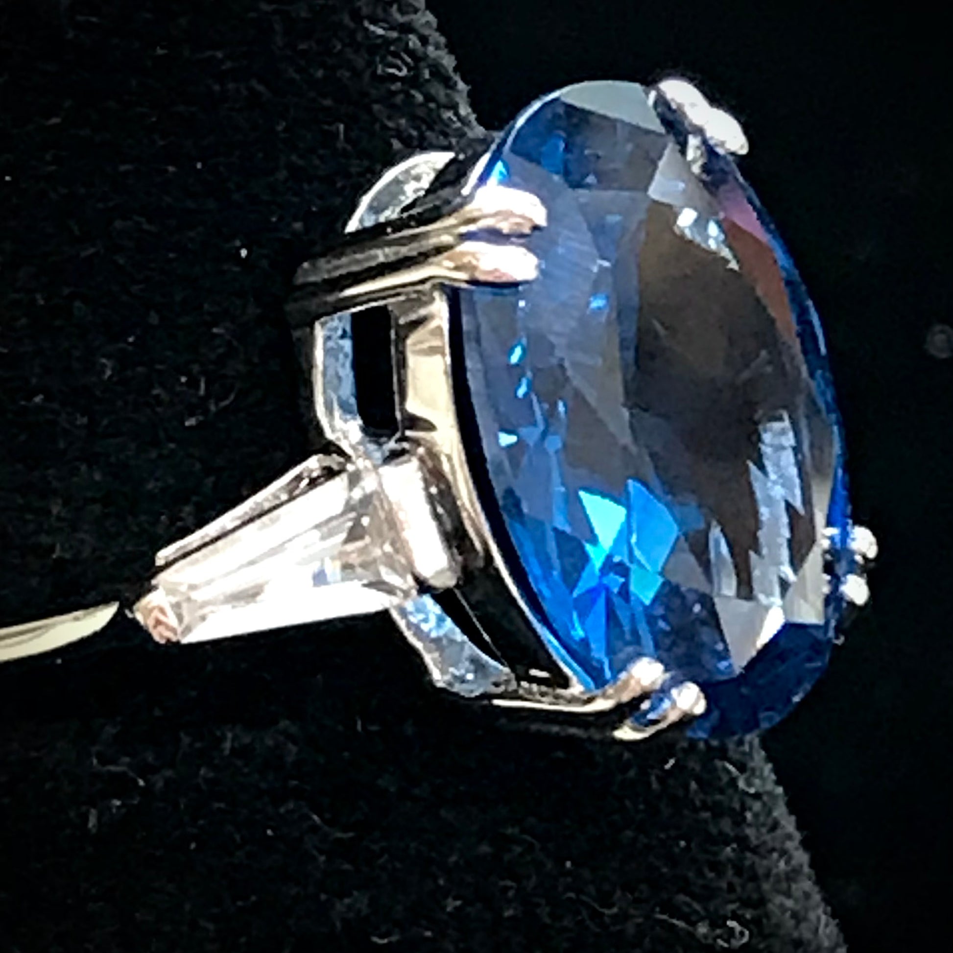 A sterling silver ring set with a faceted oval cut blue spinel and cubic zirconia baguettes.