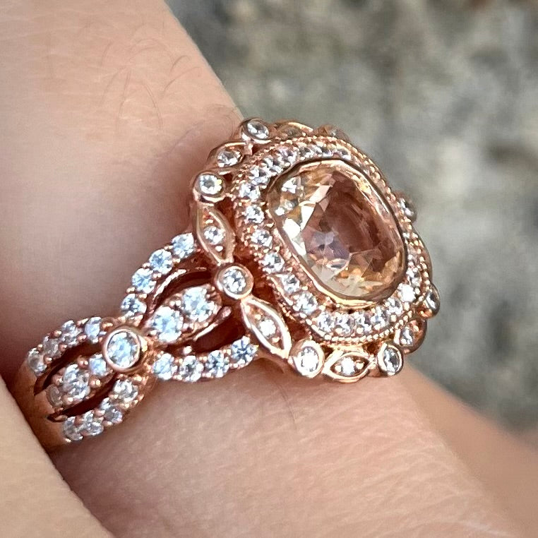 A rose gold plated ring set with a cushion cut morganite stone surrounded by cubic zirconia halos.