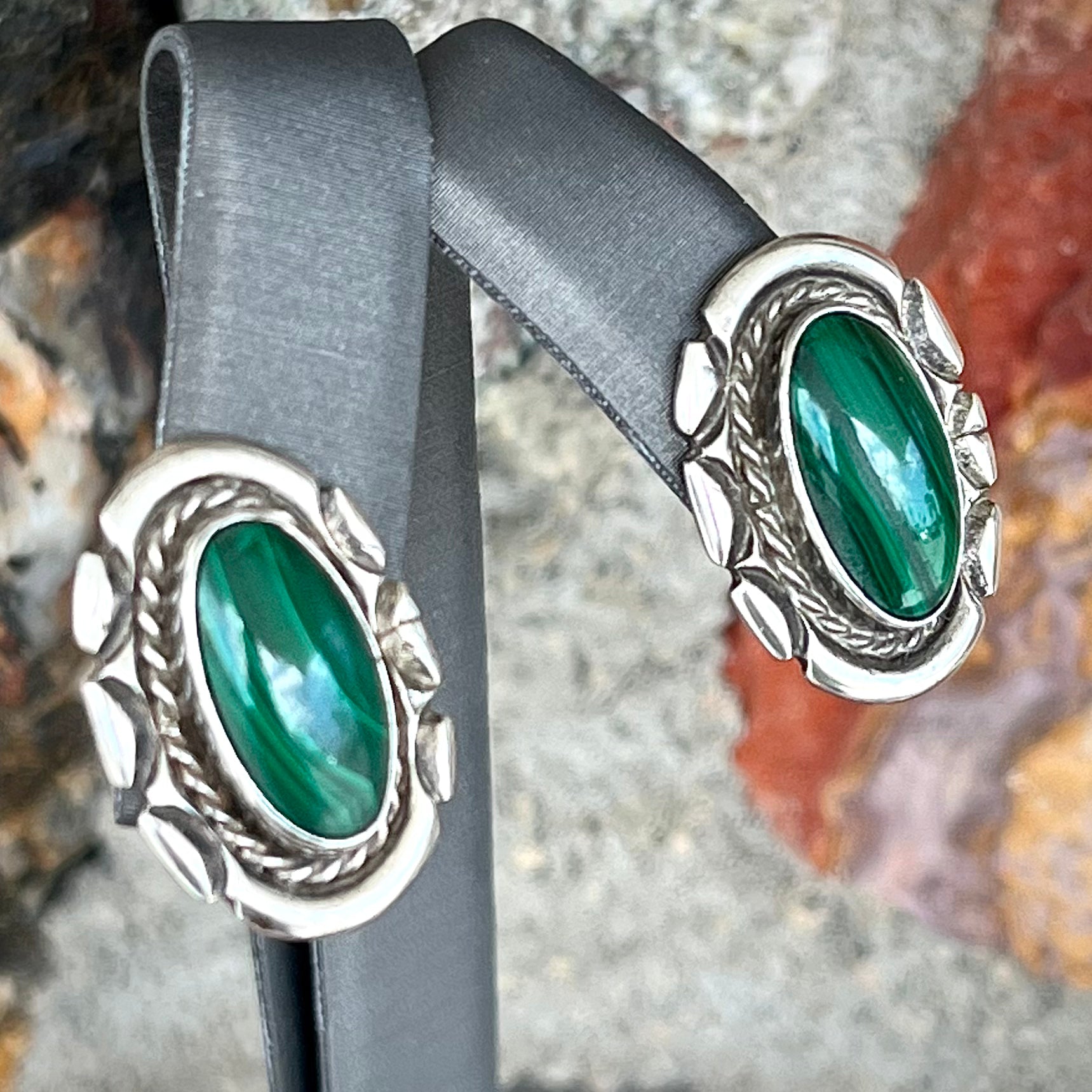 A pair of Southwest style post earrings set with oval cabochon cut malachite stones.