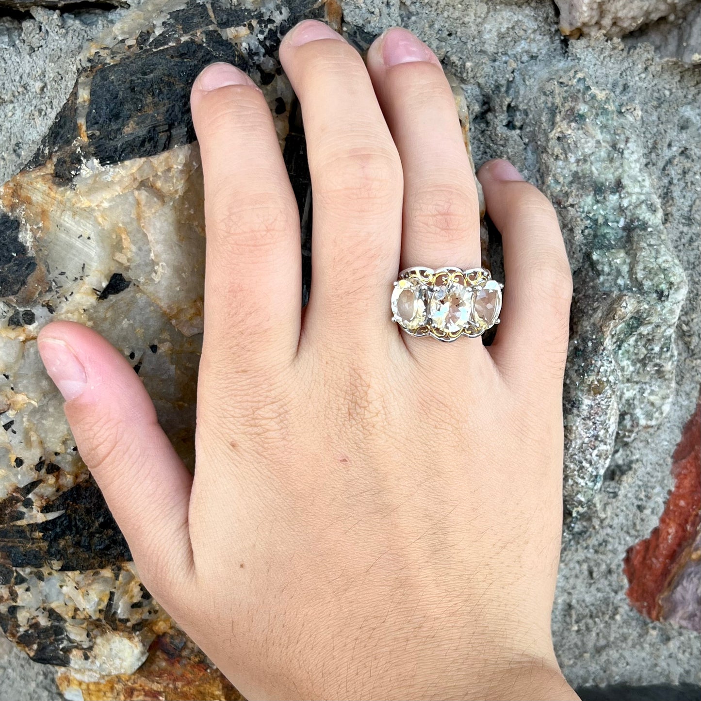 A sterling silver ring set with three oval cut golden beryl stones and yellow gold plated filigree accents.